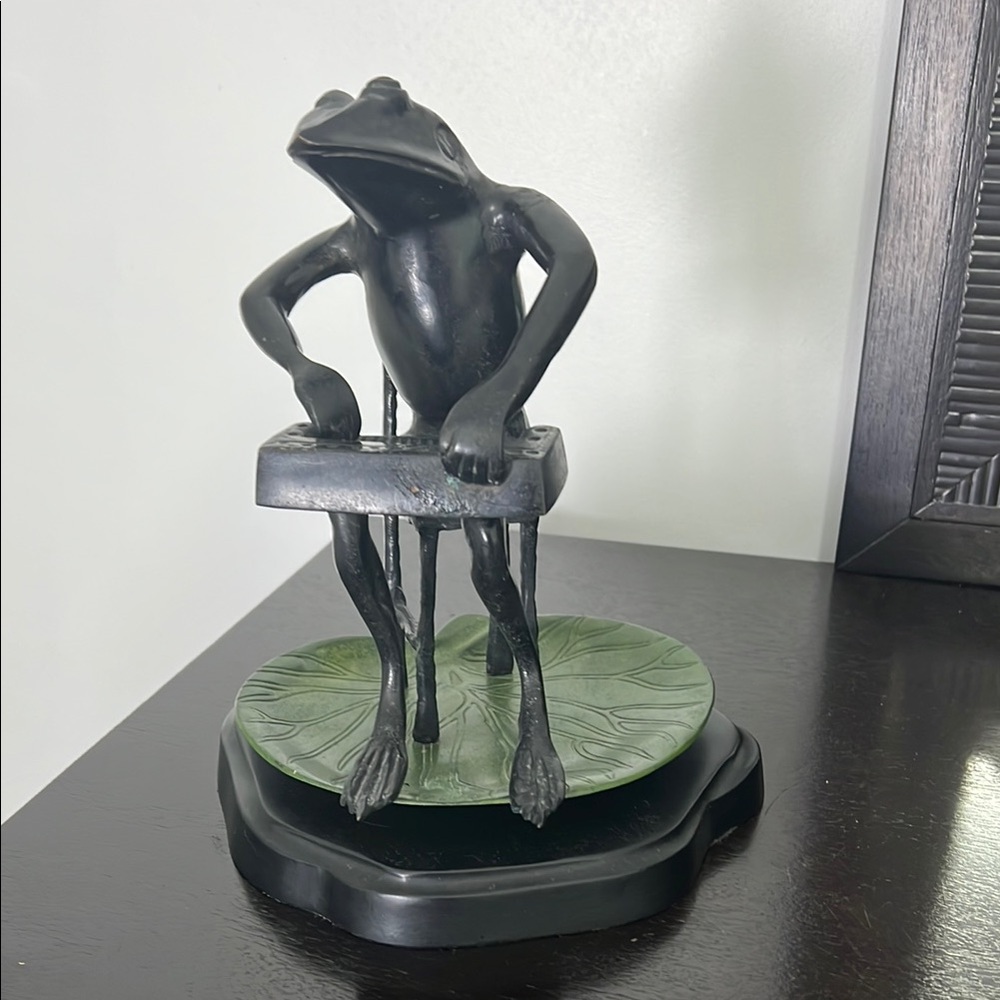 Metal sculpture of frog playing an instrument